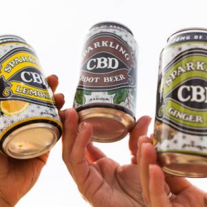 Hands holding CBD sparkling beverage cans.