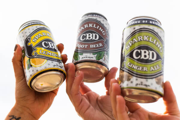 Hands holding CBD sparkling beverage cans.